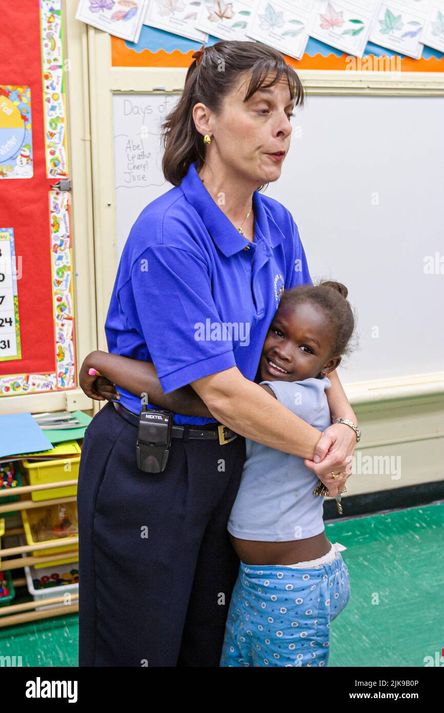 Miami Florida,Frederick Douglass Elementary School,inside primary,low income community,Black African teacher student girl female hugging classroom Stock Photo