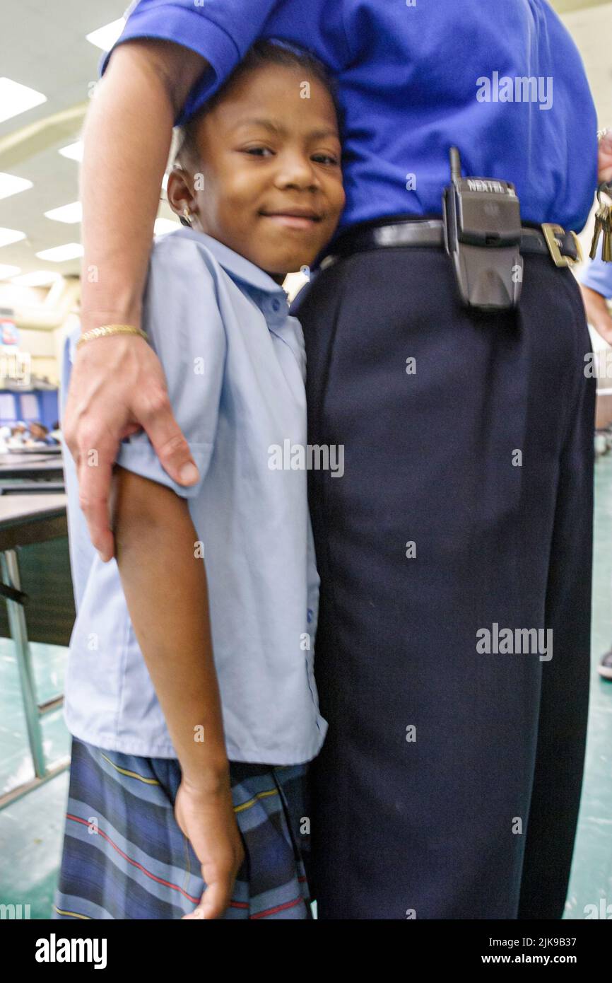 Miami Florida,Frederick Douglass Elementary School,inside interior primary,low income poverty community,Black student boy protected by adult teacher Stock Photo