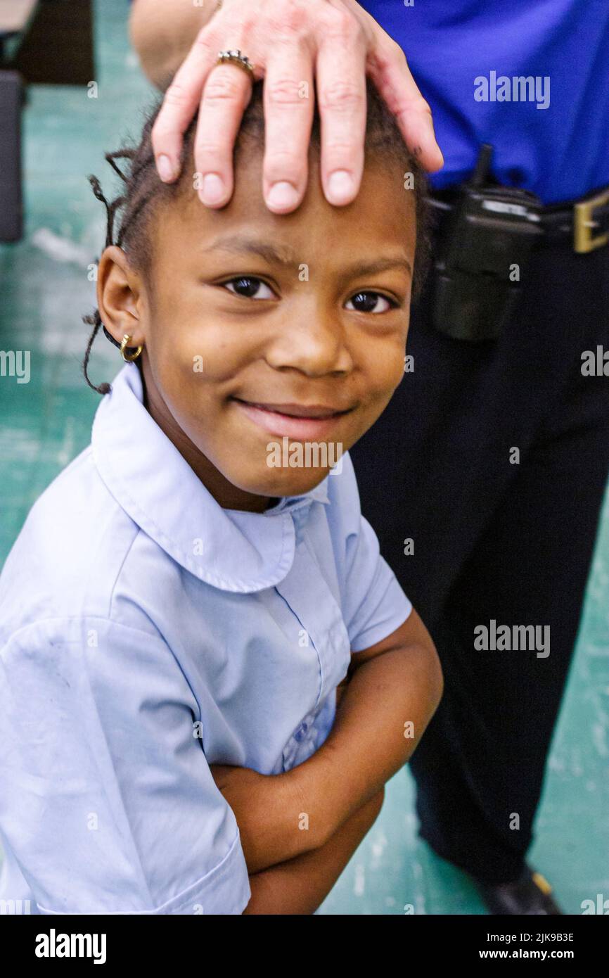 Miami Florida,Frederick Douglass Elementary School,inside interior primary,low income poverty community,Black student girl protected by adult teacher Stock Photo