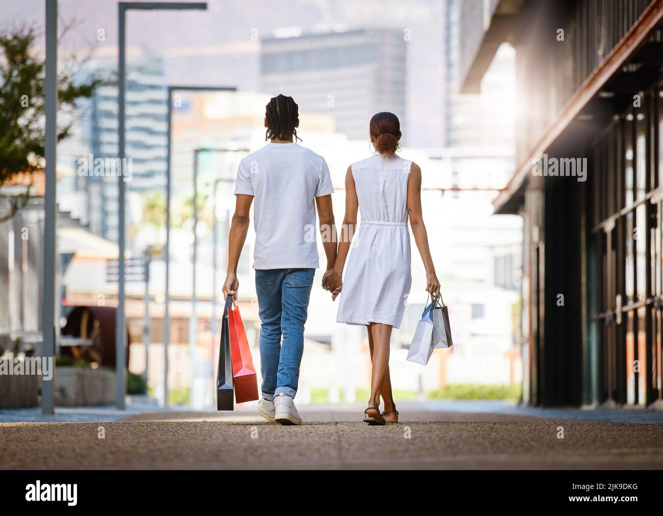 Taking her shopping is always a good idea. a young couple walking hand in hand while holding shopping bags. Stock Photo