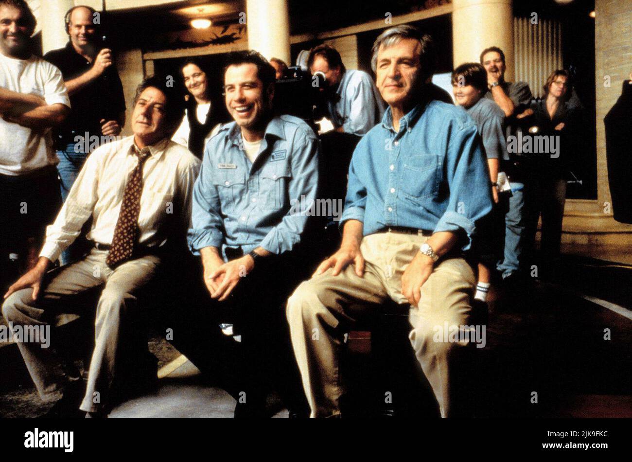 Dustin Hoffman,John Travolta, Costa-Gavras Film: Mad City (1997) Characters: Max Brackett,Sam Baily,  Director: Costa-Gavras 10 October 1997   **WARNING** This Photograph is for editorial use only and is the copyright of WARNER BROS and/or the Photographer assigned by the Film or Production Company and can only be reproduced by publications in conjunction with the promotion of the above Film. A Mandatory Credit To WARNER BROS is required. The Photographer should also be credited when known. No commercial use can be granted without written authority from the Film Company. Stock Photo