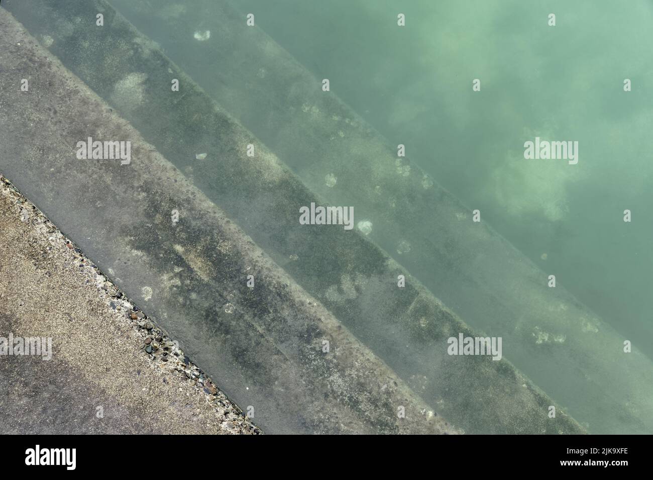 Steps sink into a salt water swimming pool, the water is slightly cloudy Stock Photo