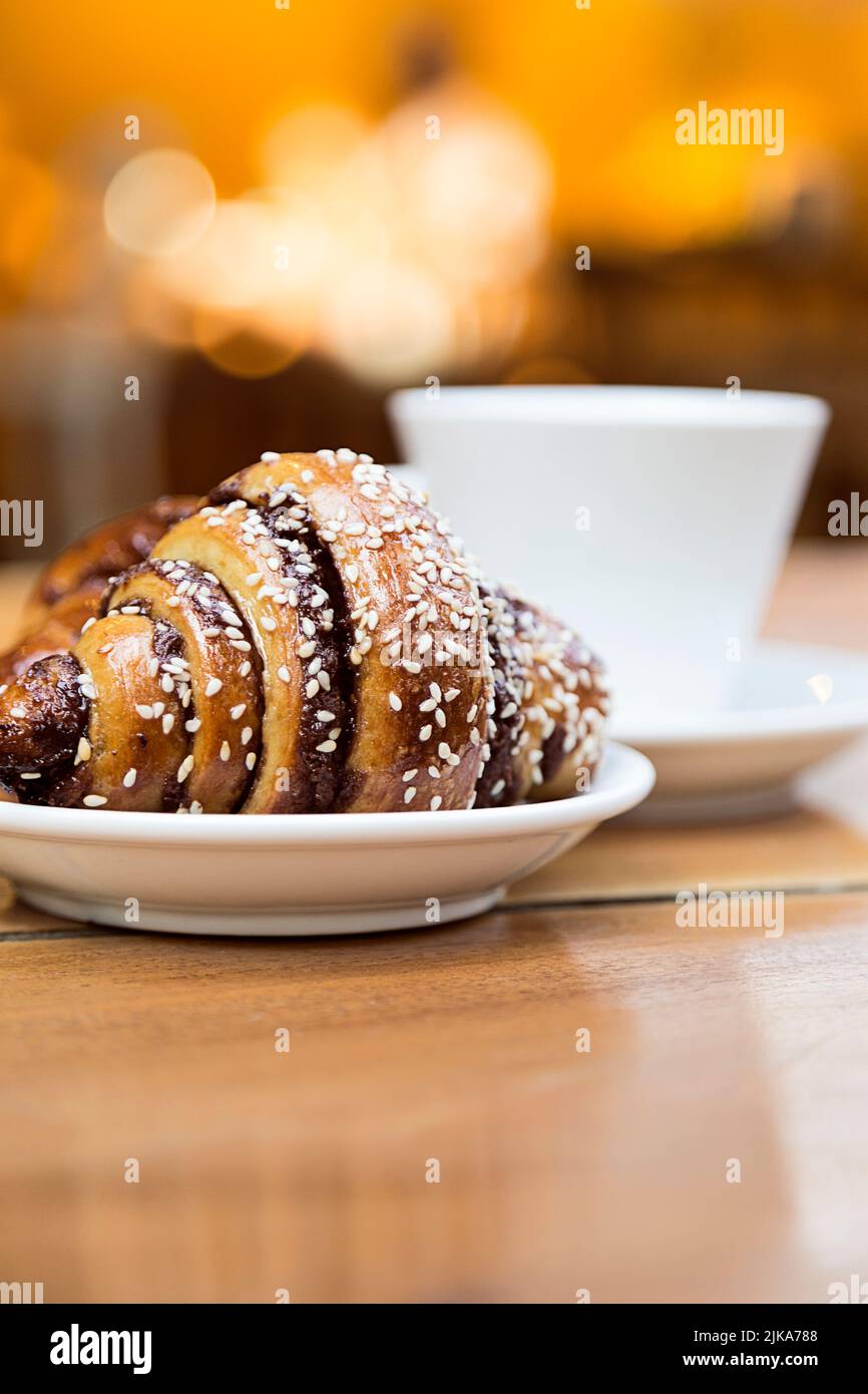 Delish chocolate croissant like rugelach and a cup of coffee on a wooden table in a restaurant Stock Photo
