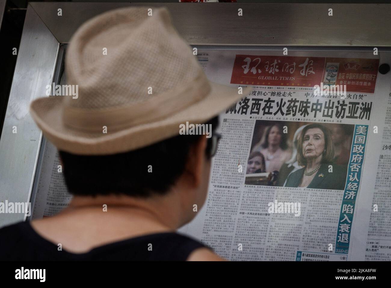 A man reads the Global Times newspaper that features a front page article about U.S. House of Representatives Speaker Nancy Pelosi's Asia tour at a street display wall in Beijing, China, August 1, 2022. The front page headline reads: 'Pelosi visits Asia in the smell of gunpowder.'  REUTERS/Thomas Peter Stock Photo