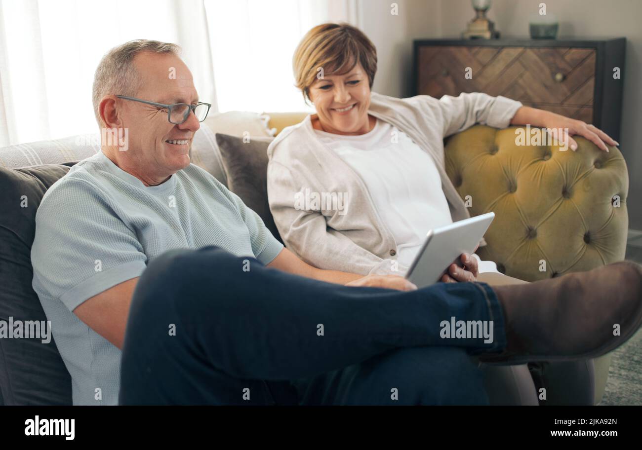 Taking a trip down digital memory lane. a mature relaxing while using a digital tablet. Stock Photo