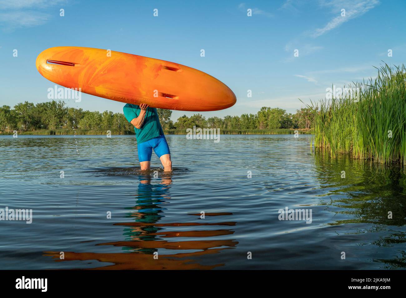 athletic, senior man is launching a prone kayak on a lake in Colorado, this water sport combines aspects of kayaking and swimming Stock Photo