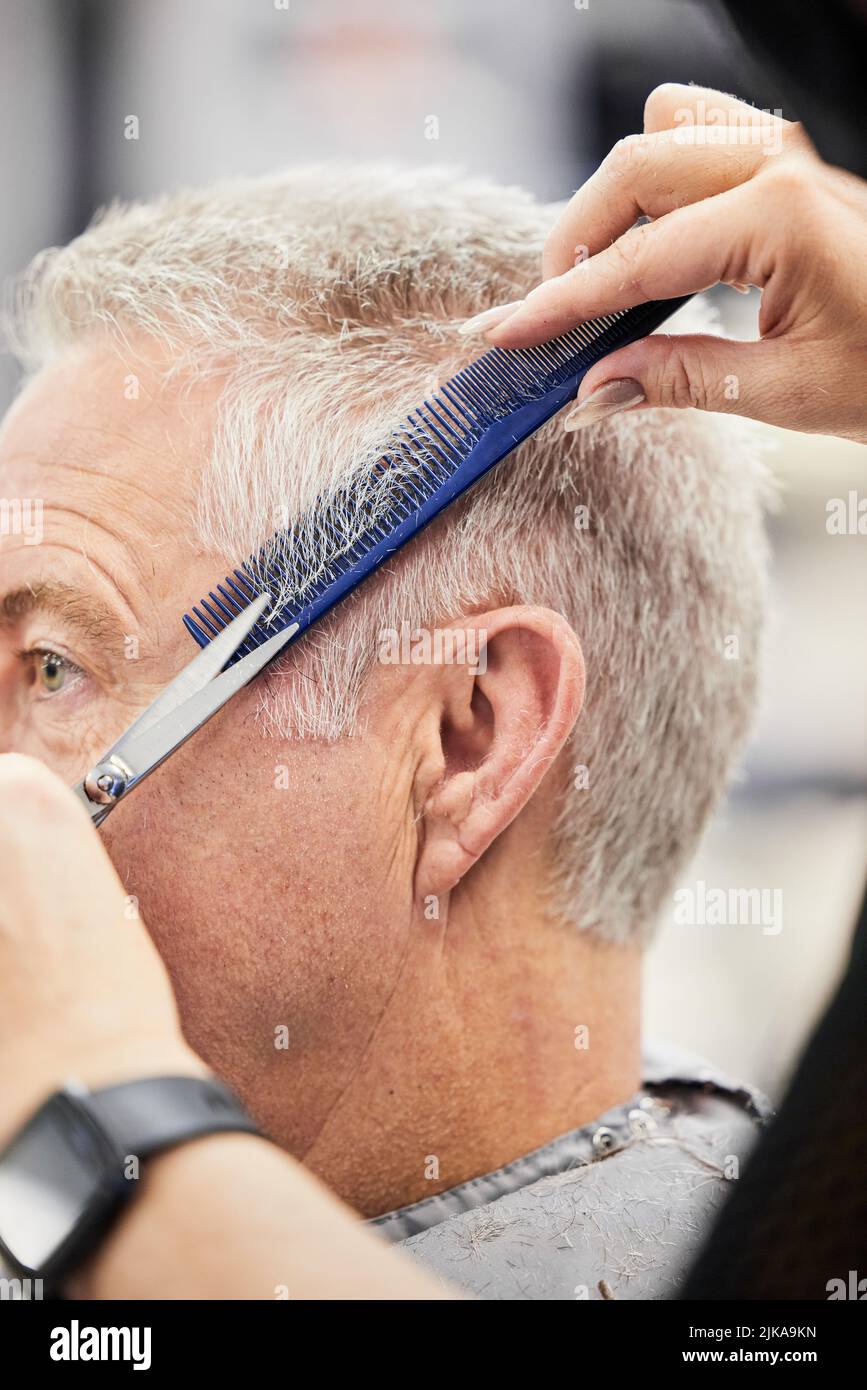 A good haircut will instantly boost your confidence too. a mature man getting a haircut in a salon. Stock Photo