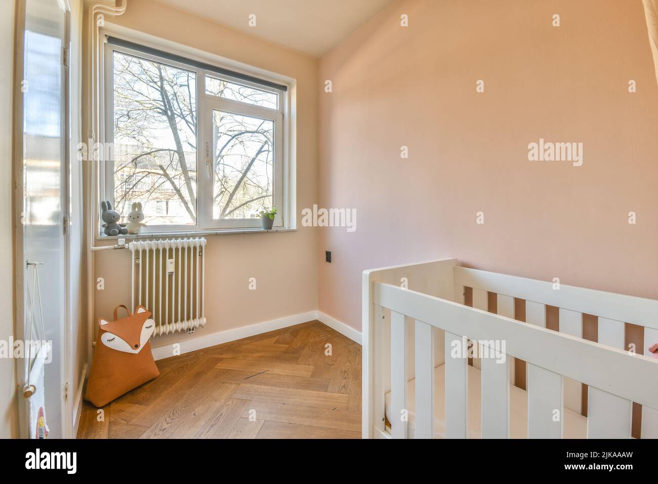 Interior of white room with baby crib and armchair near window with