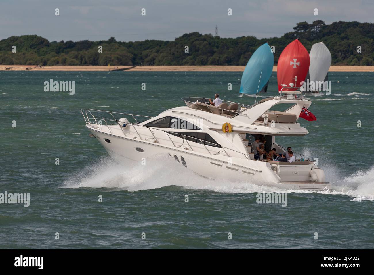 The Solent, southern England, UK. 2022. Luxury motorboat crossing the path of yachts competing in Cowes Week racing off the Hampshire coast near Calsh Stock Photo
