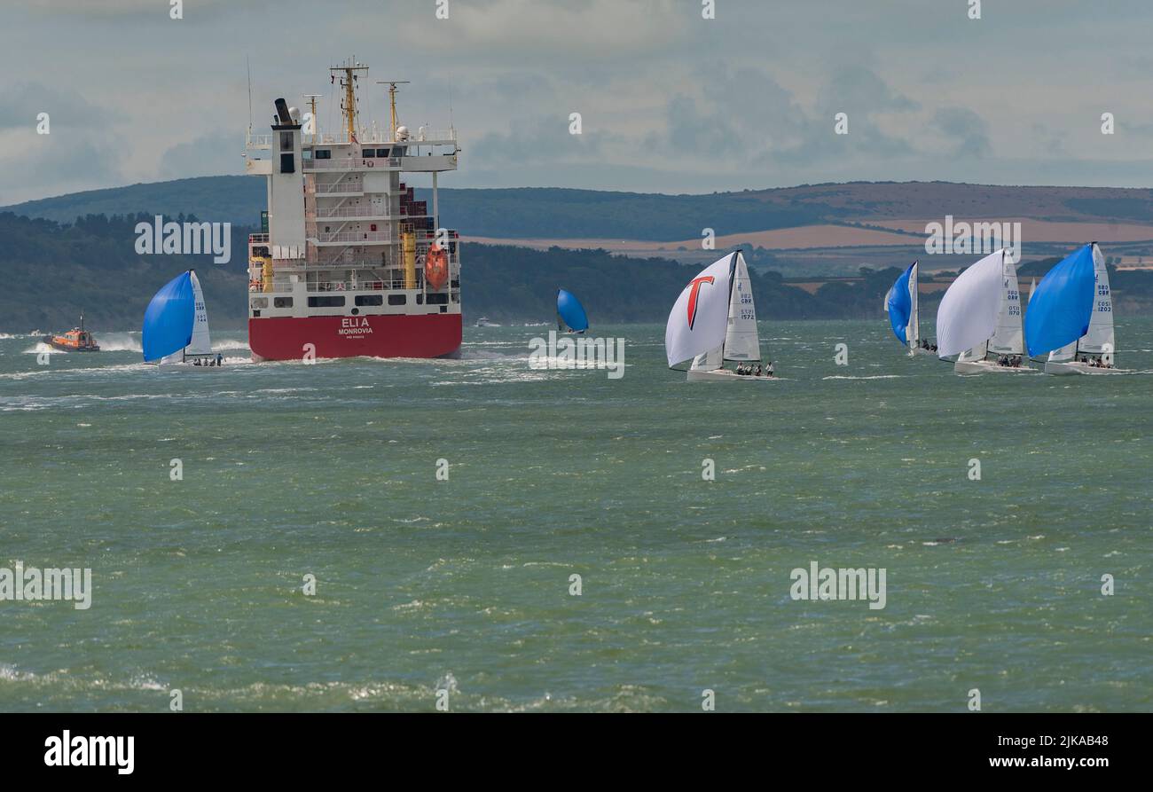 Solent, southern England, UK. 2022. Cowes week and racing yachts close to the container carrier ship Eli A on the Solent with a backdrop if the Isle o Stock Photo