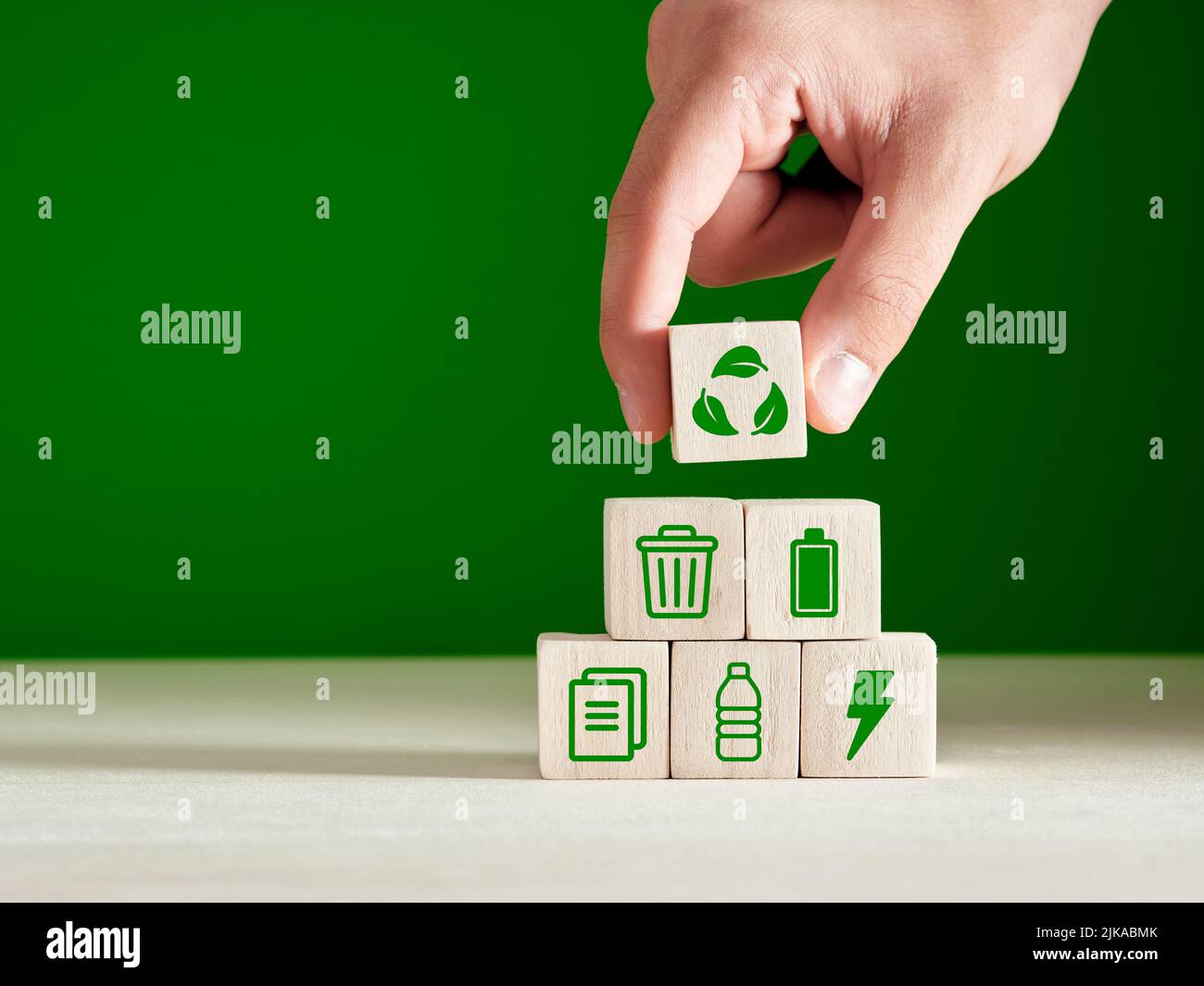 Recycling and environmental protection concept. Environment sustainable development. Hand puts recycling product material symbols on green background. Stock Photo