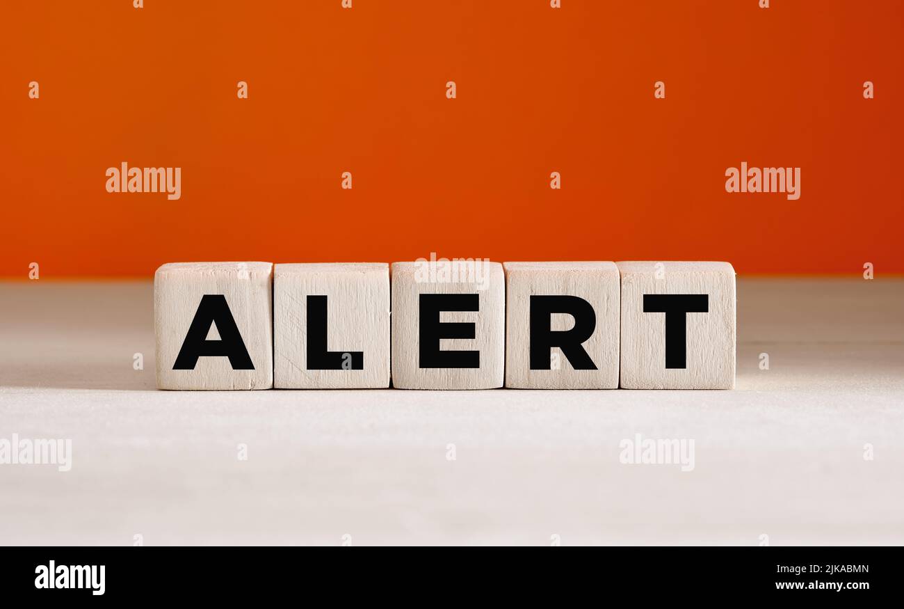 The word alert on wooden cubes on orange background with copy space. Stock Photo