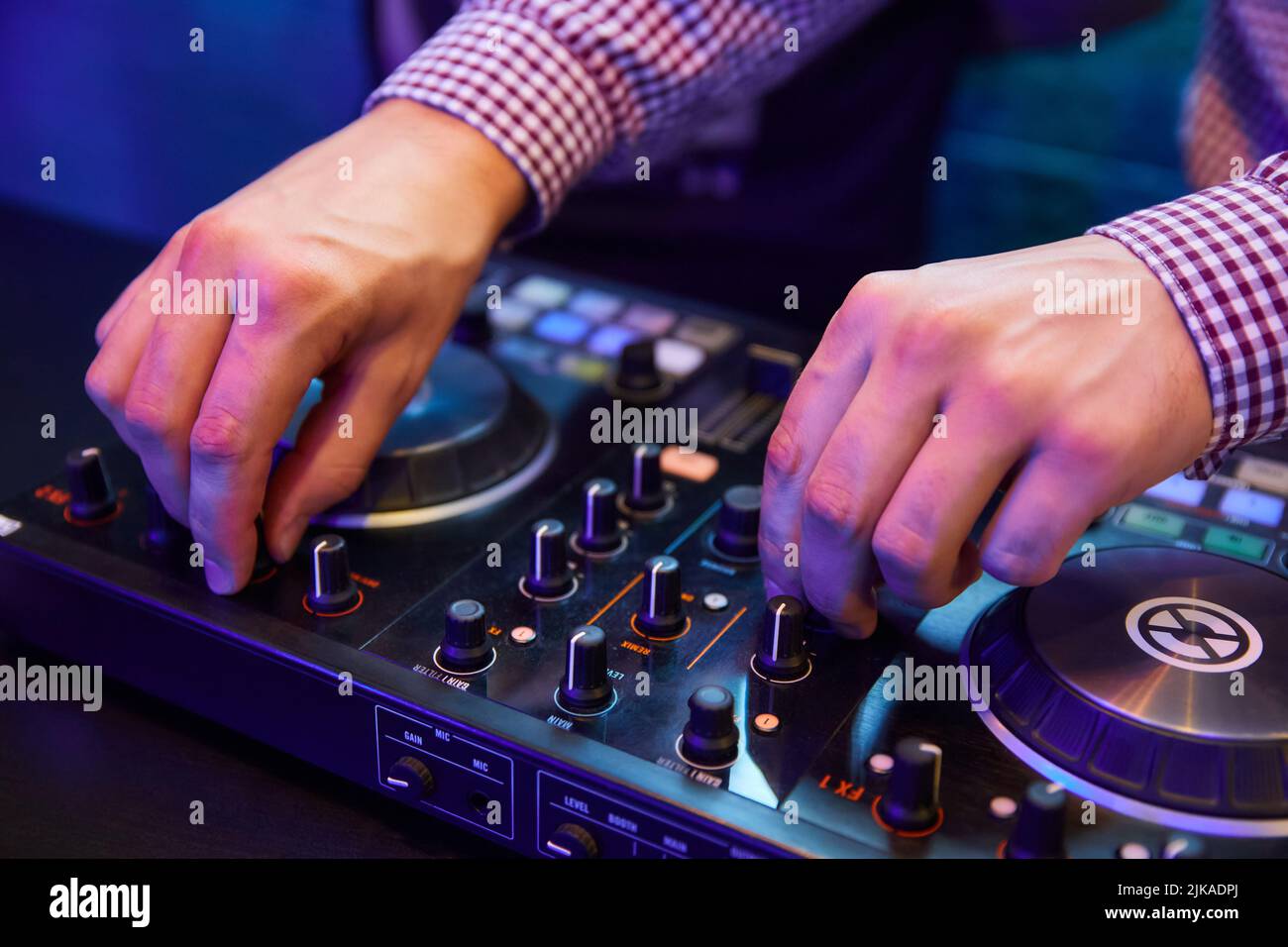 Dj playing music with turntables and sound mixer on stage in night club