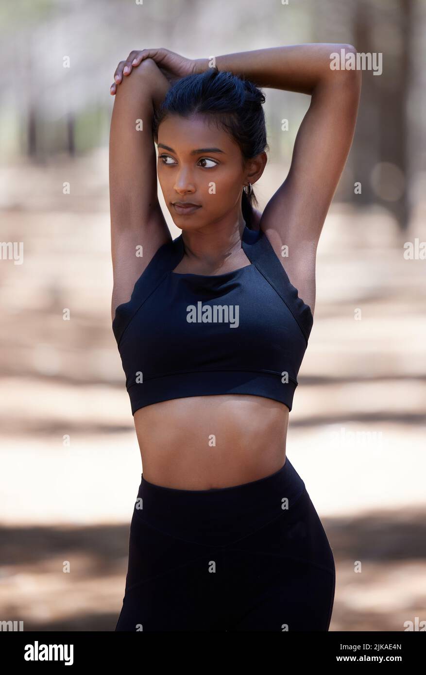 My health comes first. an attractive young woman standing and stretching before her workout outdoors. Stock Photo