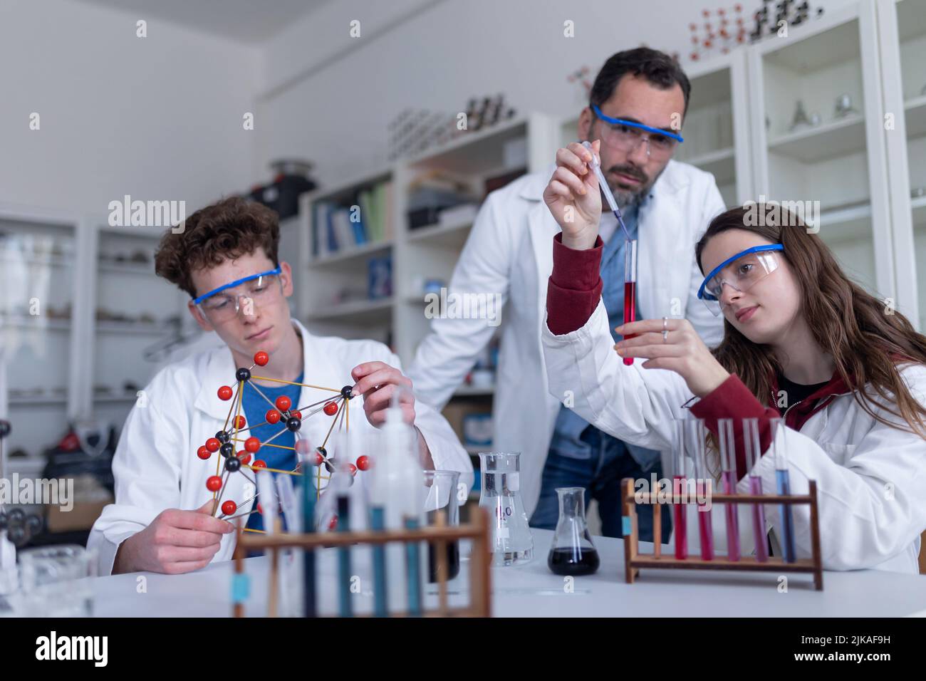 Science students with teacher doing chemical reaction experiment in the