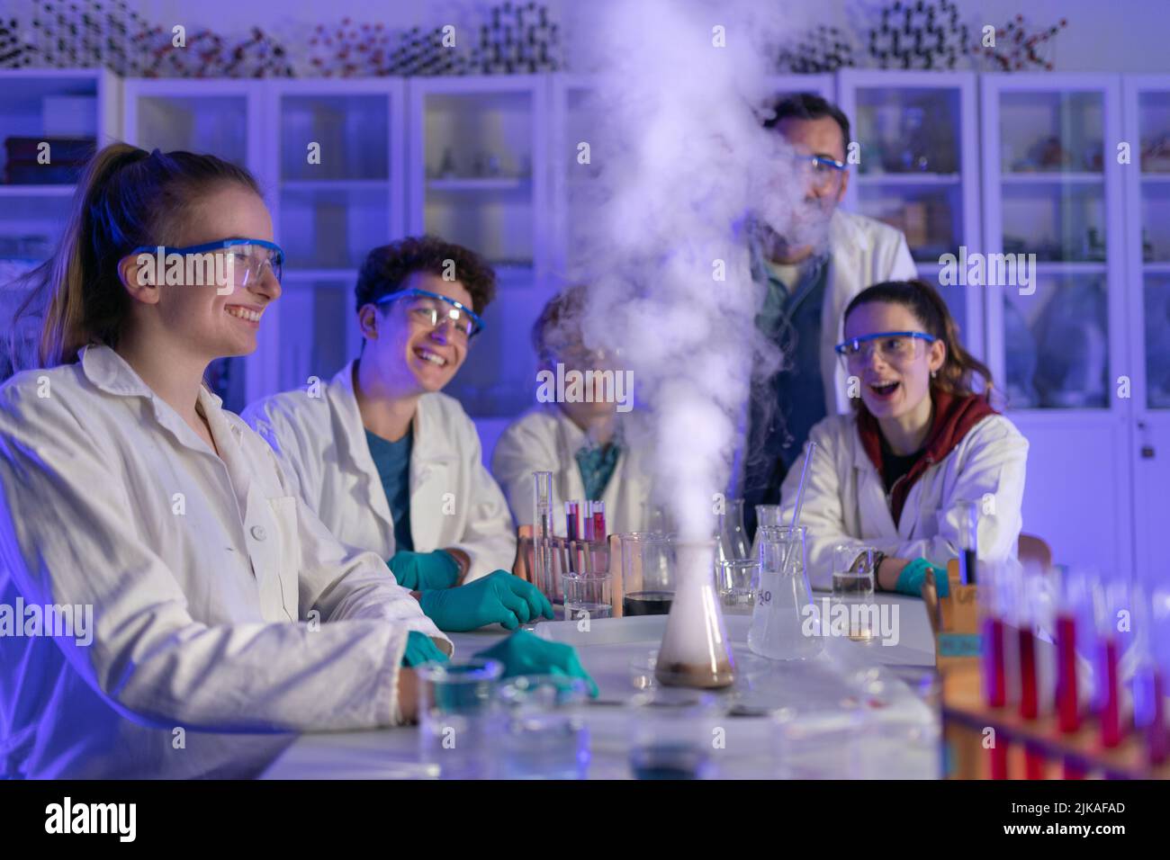 Excited science students with teacher doing chemical experiment in the laboratory at university. Stock Photo