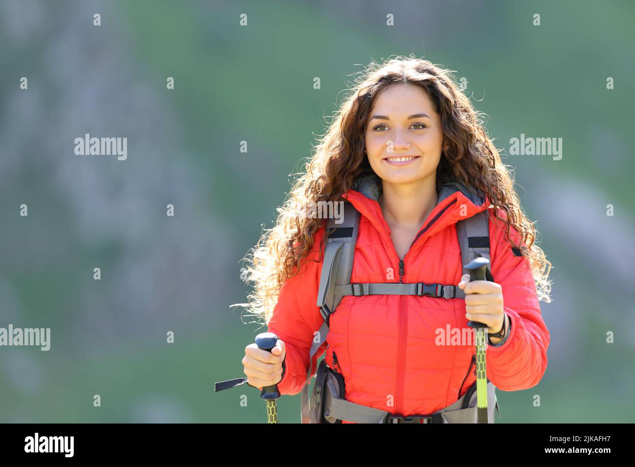 Happy hiker in red walking towards camera in the mountain Stock Photo