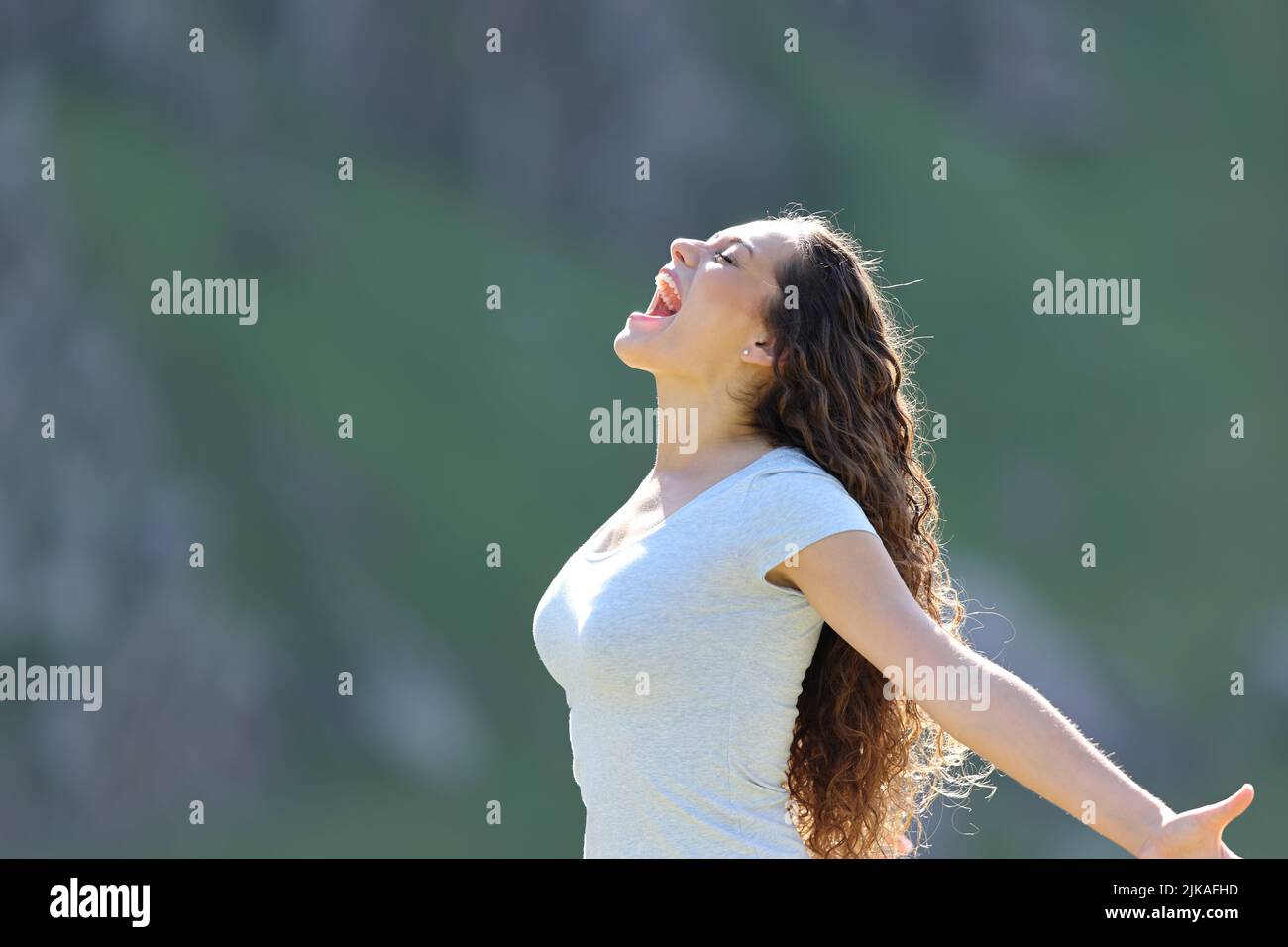 Profile of an excited woman screaming in the mountain Stock Photo