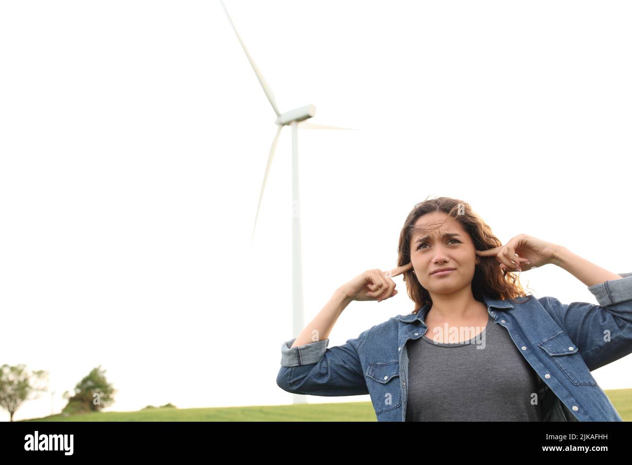 Angry woman covering ears listening wind mill noise in a mountain Stock Photo