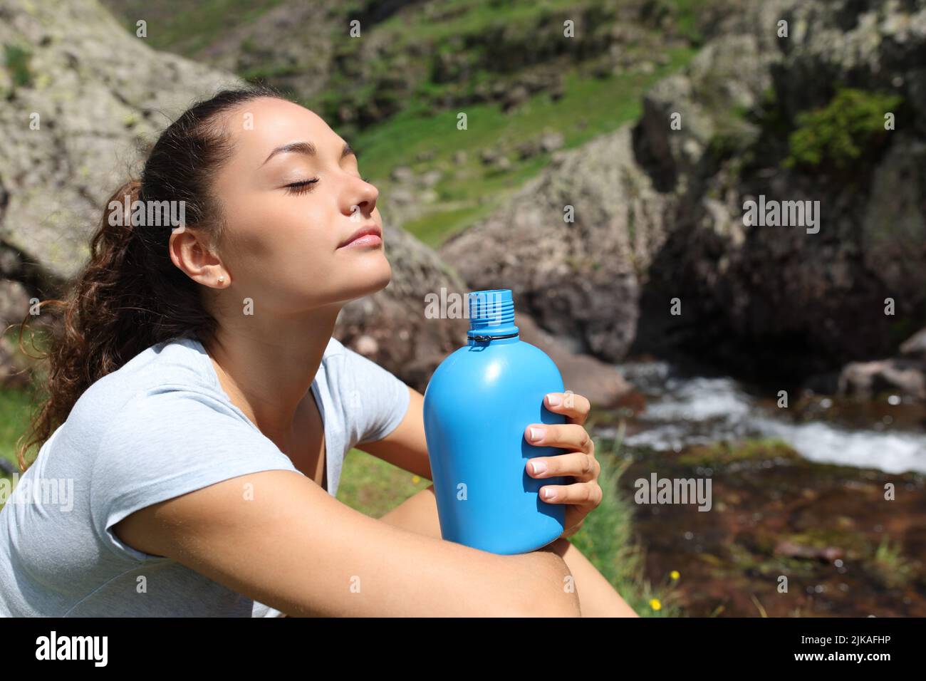 Woman holding canteen breathing fresh air in a riverside in the mountain Stock Photo
