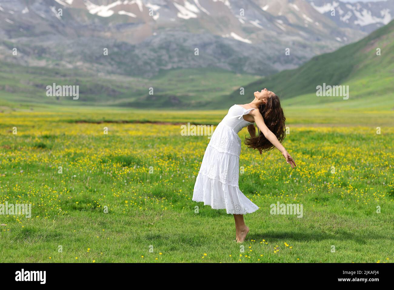 Side view portrait of a woman in white dress screaming in the mountain Stock Photo