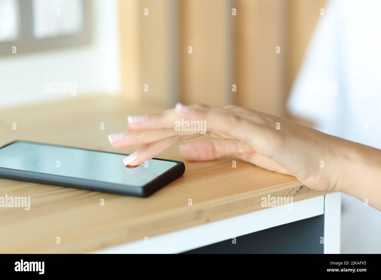 Close up portrait of a woman hand stopping alarm on smart phone in a bedroom Stock Photo