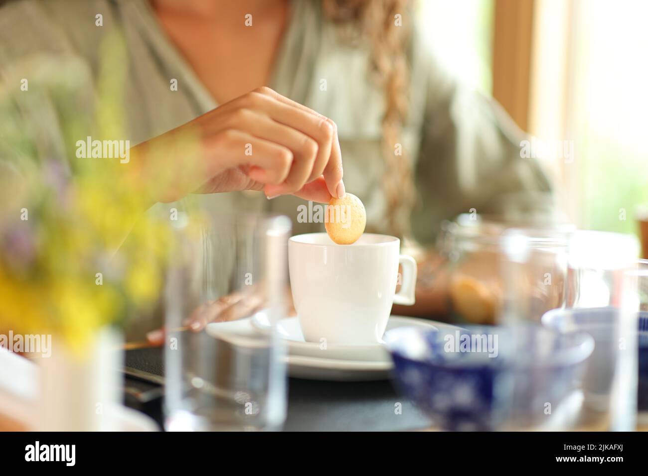 Close up portrait of a woman hand dipping cookie in milk in a restaurant Stock Photo