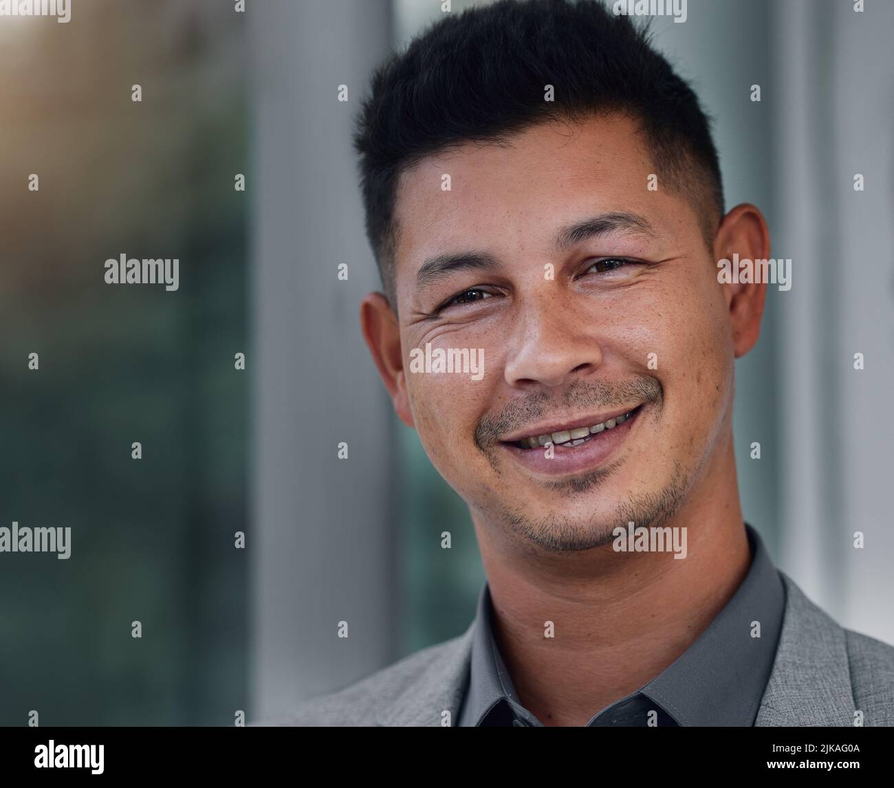 Working overtime wont steal my smile. a handsome young businessman standing alone in the office during a late shift. Stock Photo