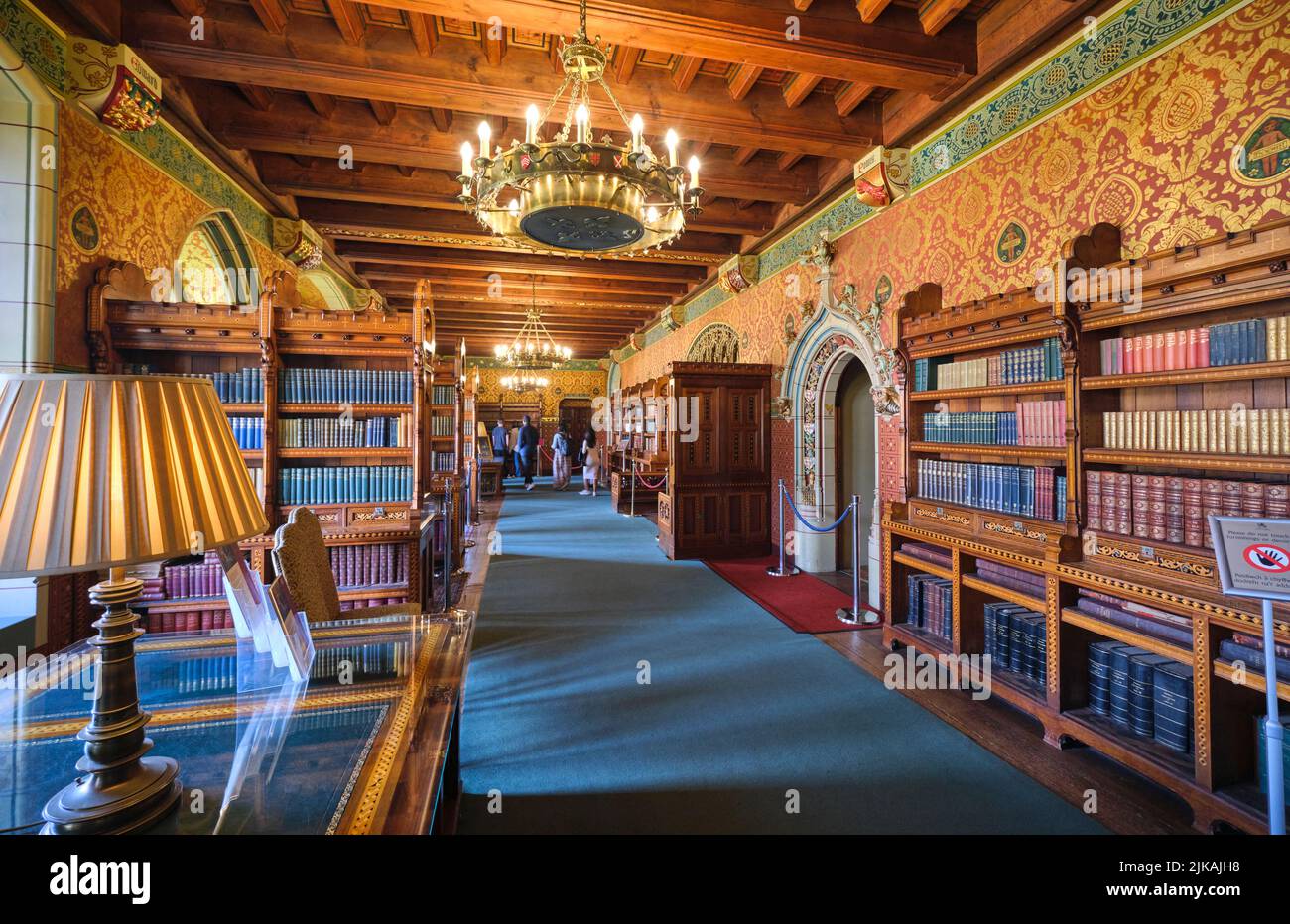 Grand chandelier and rows of books on bookslelves. In the richly decorated library at Cardiff Castle in Cardiff, Wales, United Kingdom. Stock Photo