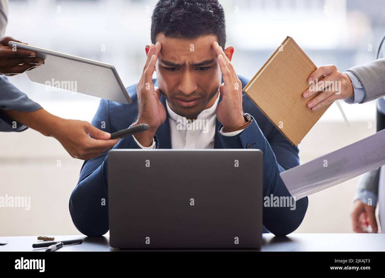 My head feels like its going to explode. a businessman looking overwhelmed in a demanding office environment. Stock Photo