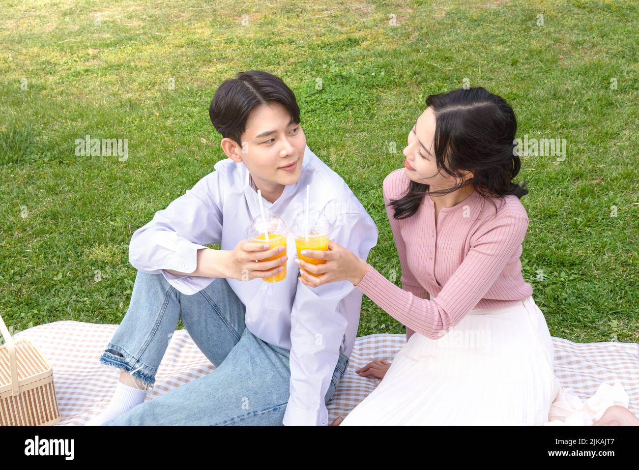 Asian Korean couple enjoying spring picnic drinking beverage Stock Photo
