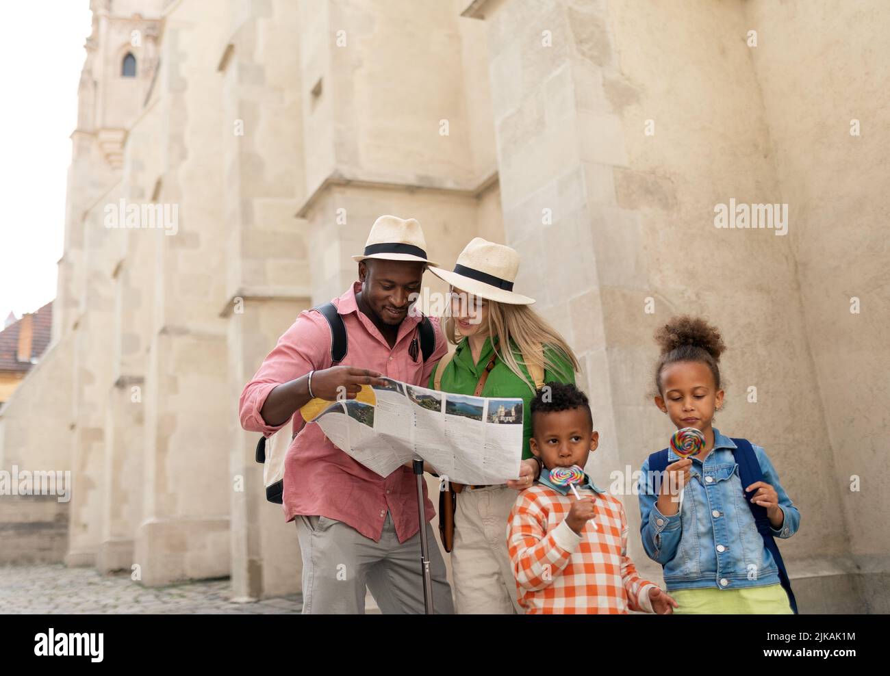 Multiracial family travel together in old city centre, looking at map. Stock Photo