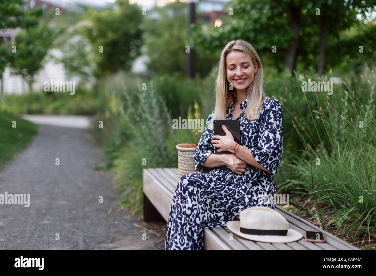Mature woman sitting in park bench, enjoying time for herself. Stock Photo