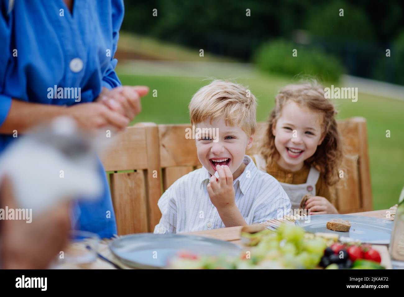 Happy kids enjoying garden party with family, having fun and eating together. Stock Photo
