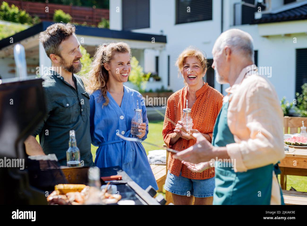 Multi generation family grilling outside on backyard in summer during garden party Stock Photo