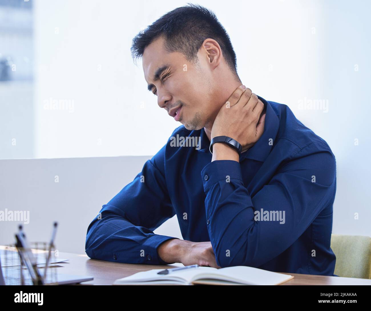 I could cry with how painful this is. a young businessman experiencing neck pain while working
