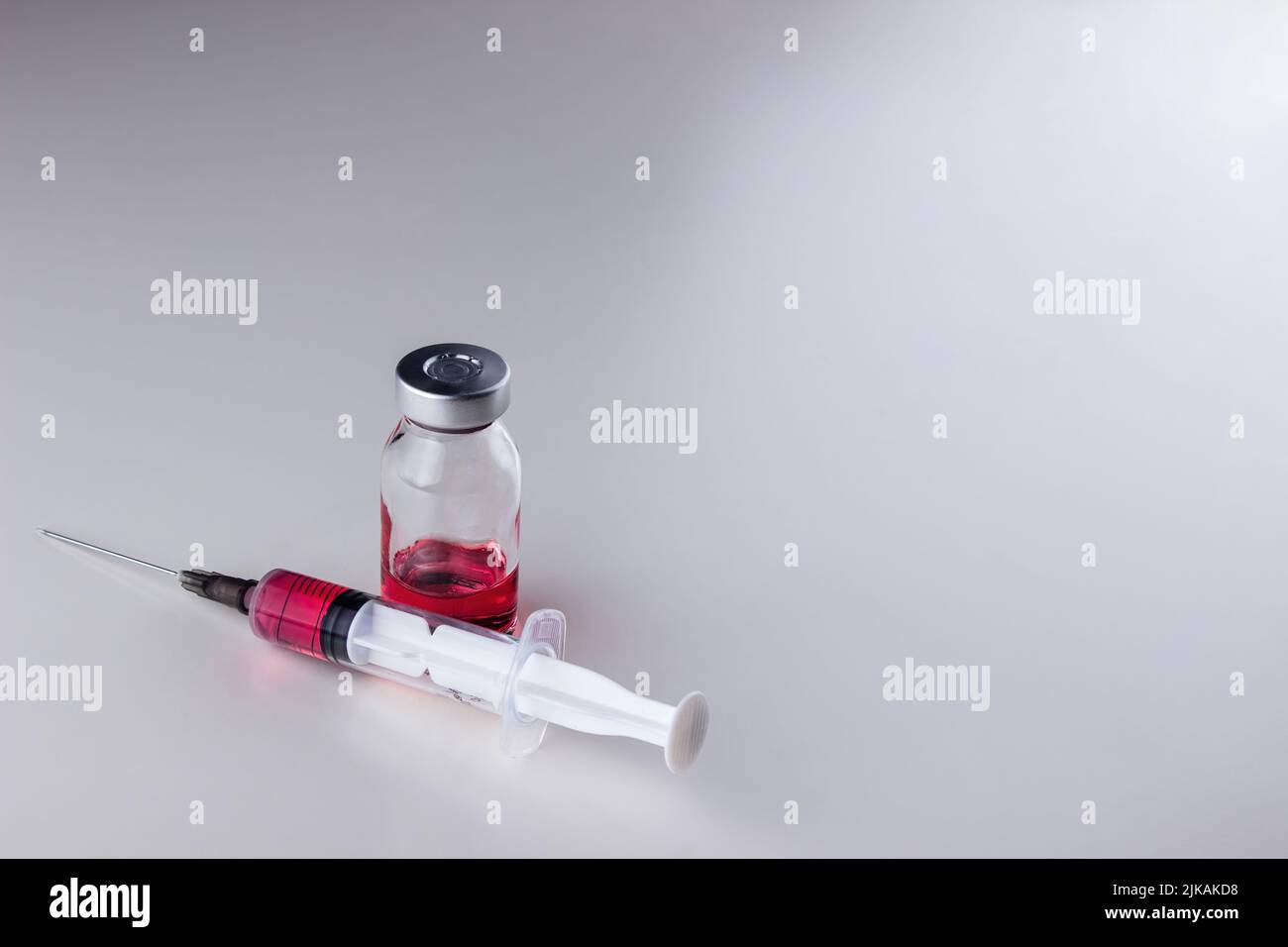 Red liquid (vitamin B12) in a disposable syringe with a needle and in a