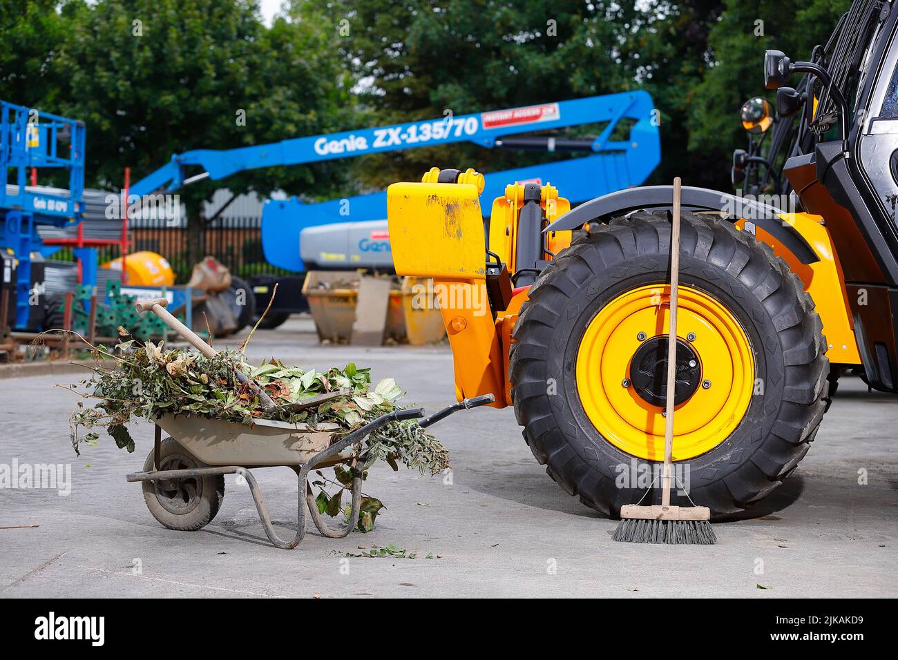 A wheelbarrow and brush pictured with JCB Telehandlers at a plant hire yard Stock Photo