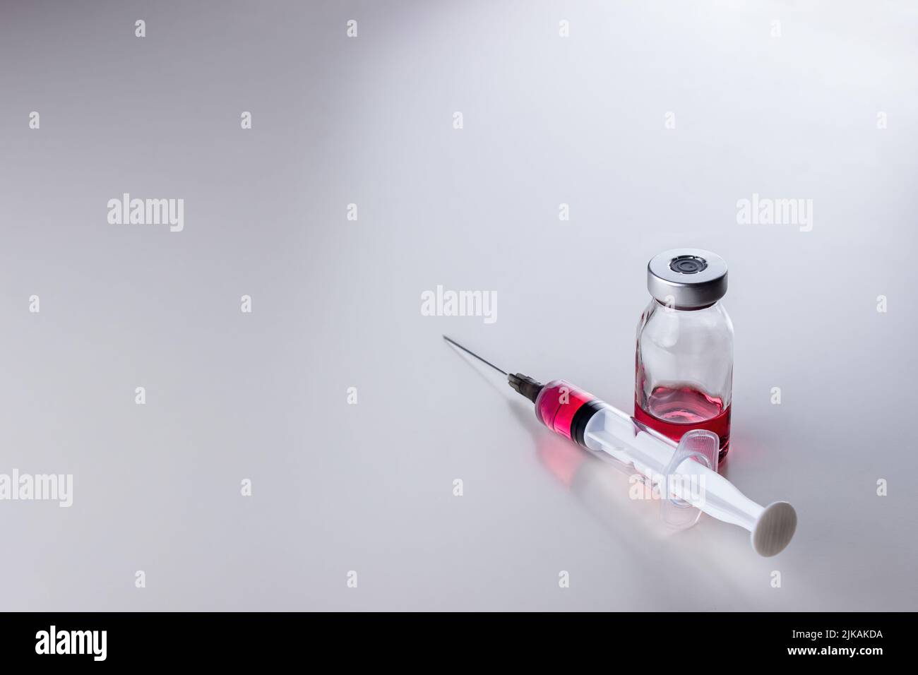 Red liquid (vitamin B12) in a disposable syringe with a needle and in a