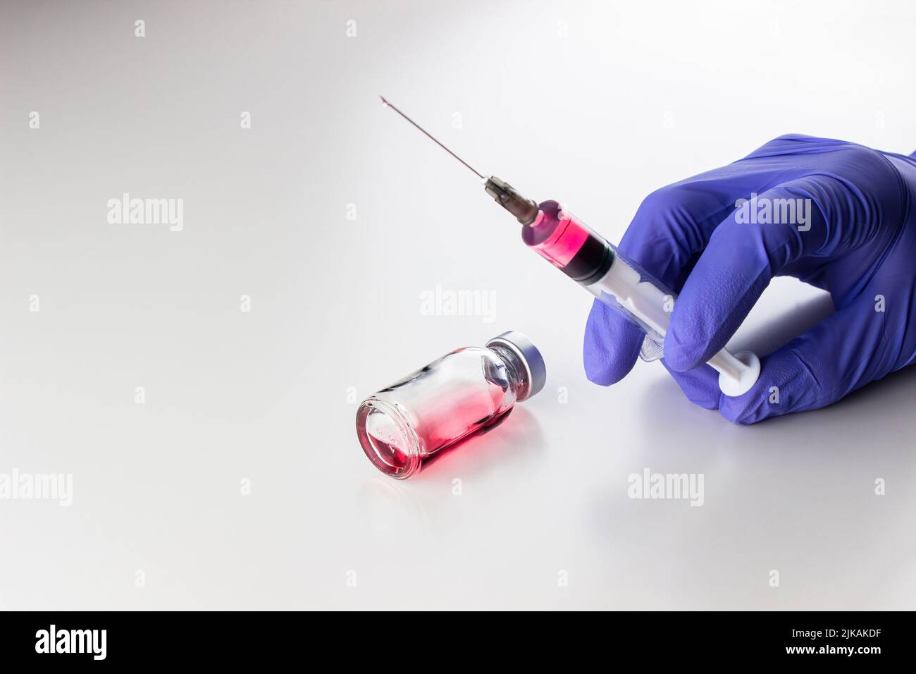 a disposable syringe with a needle and an ampoule with red (vitamin B12