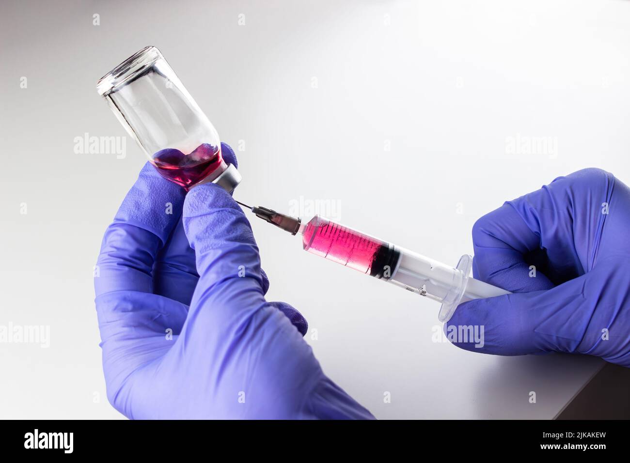 a disposable syringe with a needle and an ampoule with red (vitamin B12