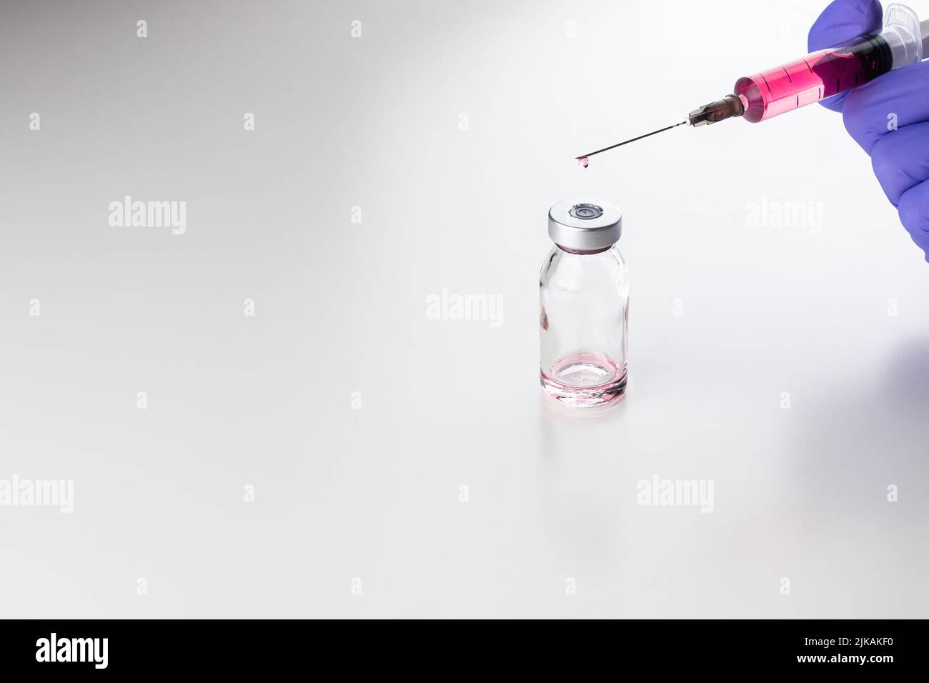 a disposable syringe with a needle and an ampoule with red (vitamin B12