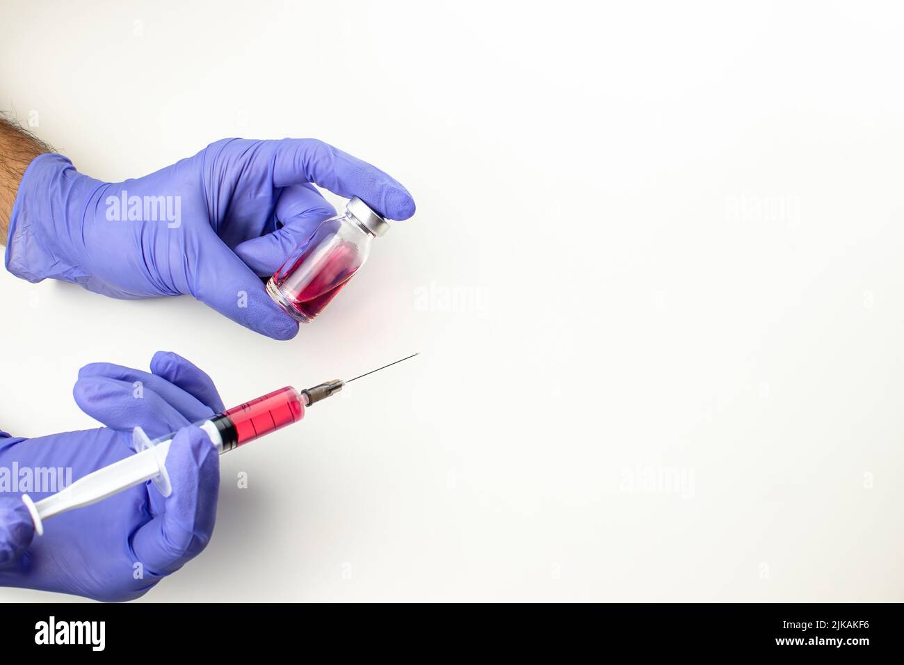 a disposable syringe with a needle and an ampoule with red (vitamin B12