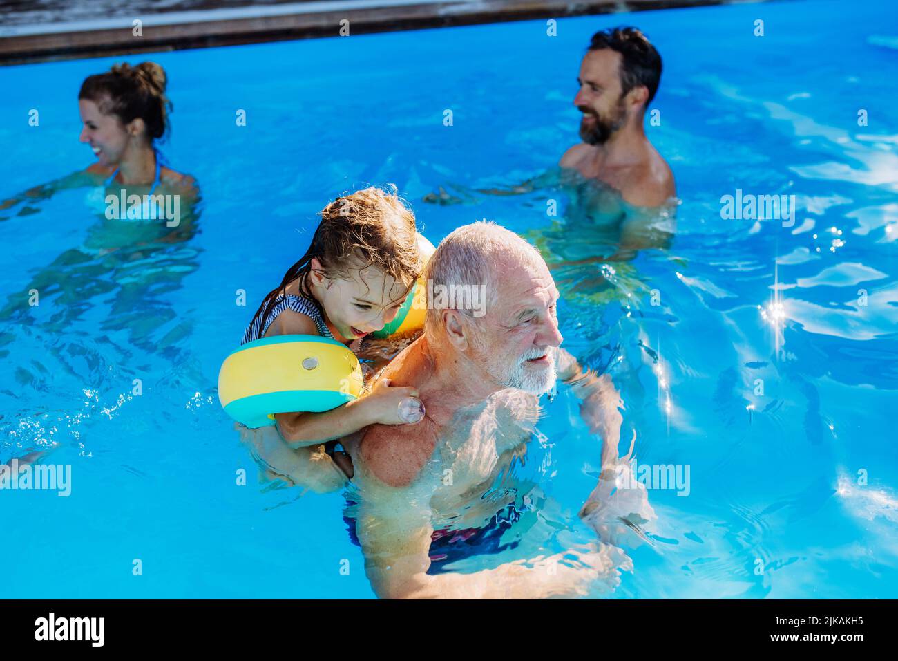 Multi generation family having fun and enjoying swimming in backyard pool during summer holiday. Stock Photo