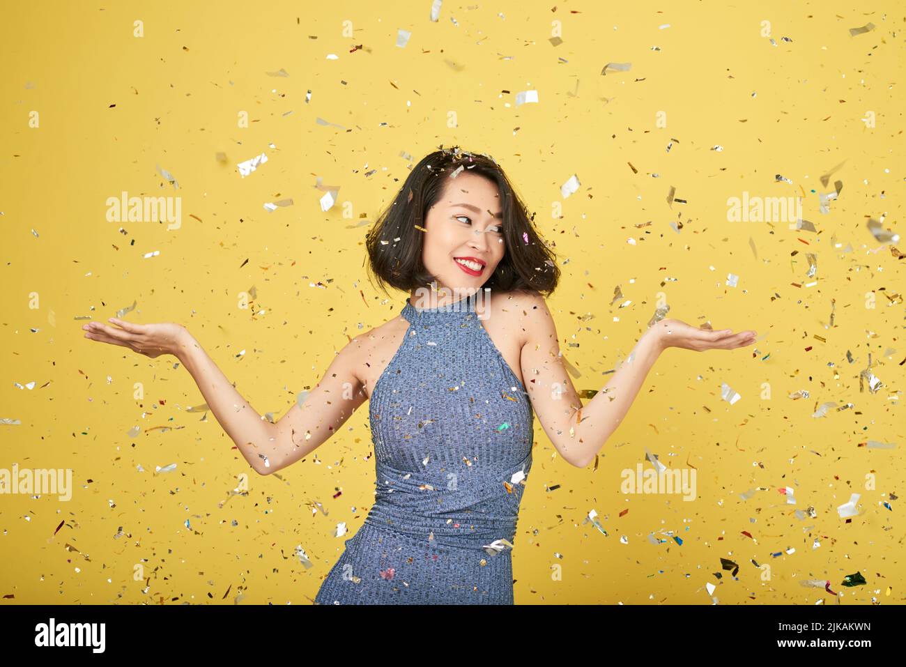 Lovely happy young woman standing in falling confetti Stock Photo