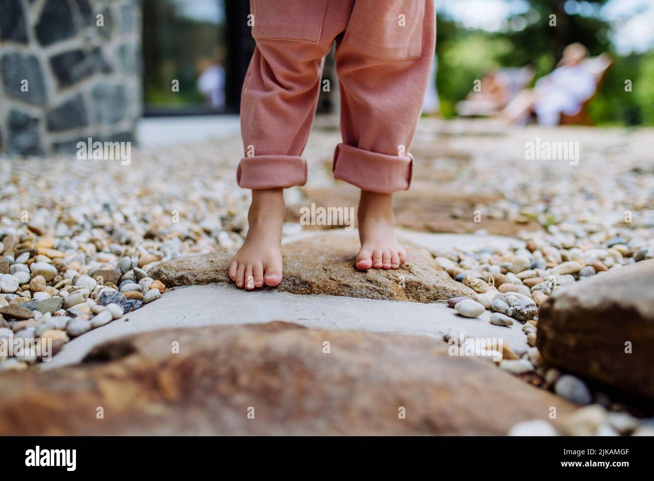 Close-up of little girls barefoot legs, first steps at backyard during summer day. Stock Photo