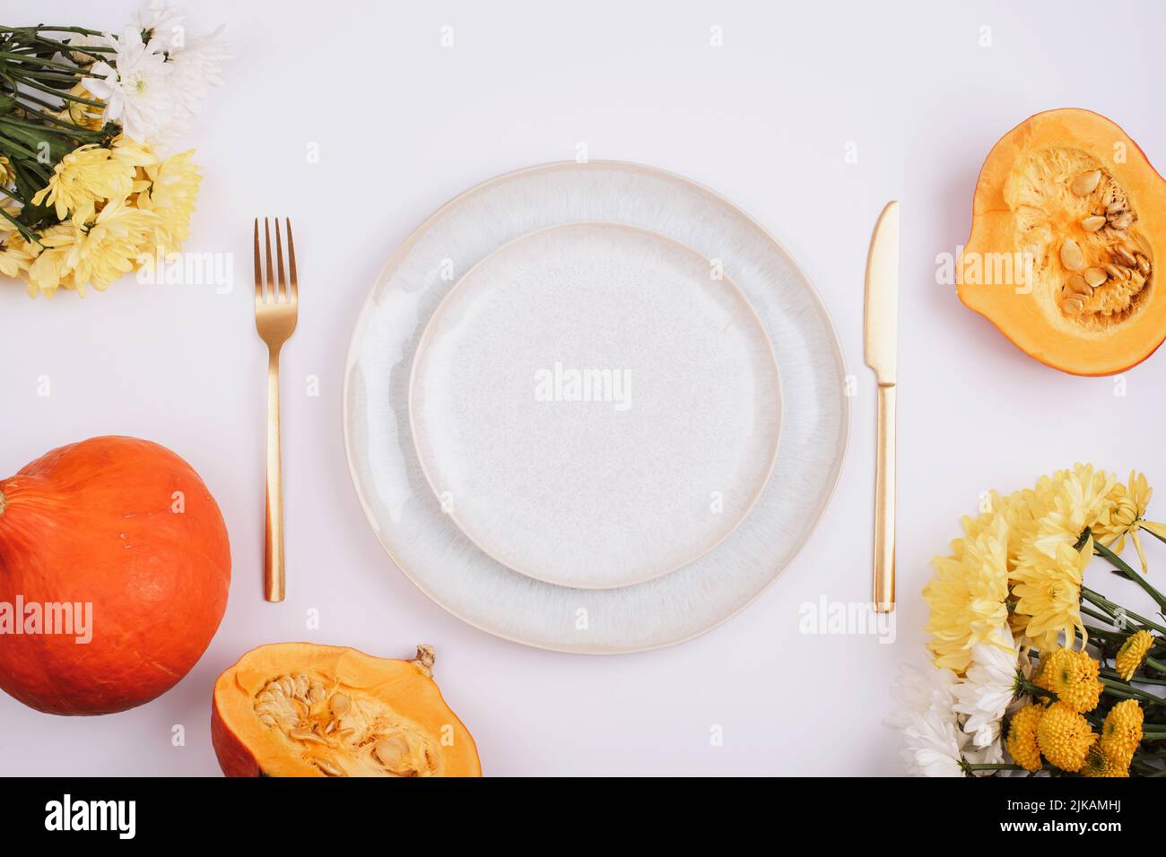 Stylish table setting, yellow dahlia flowers, pumpkins and plate on white table. Top view, flat lay Stock Photo