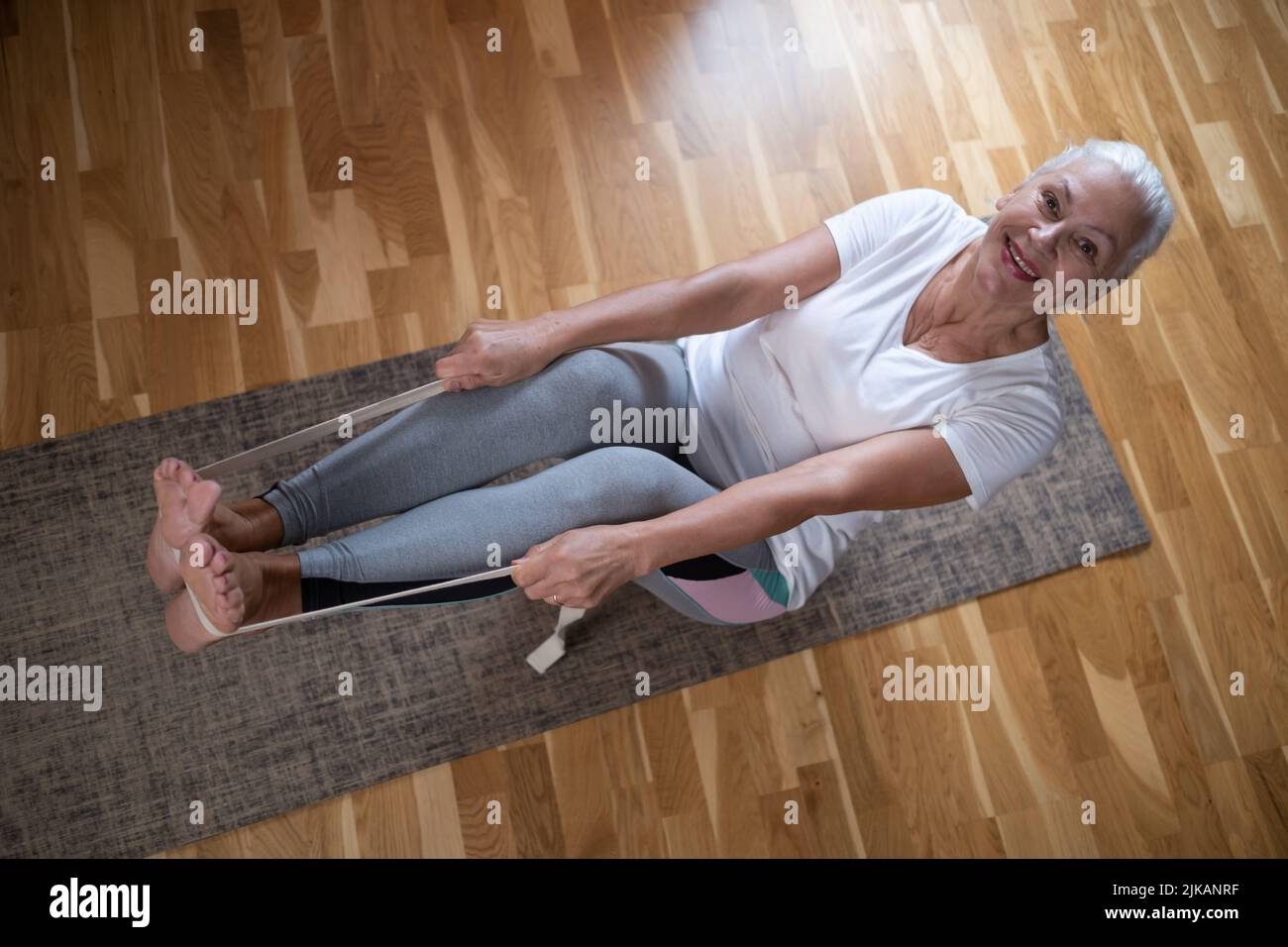 Senior caucasian woman doing abs exercises, sitting in boat yoga pose