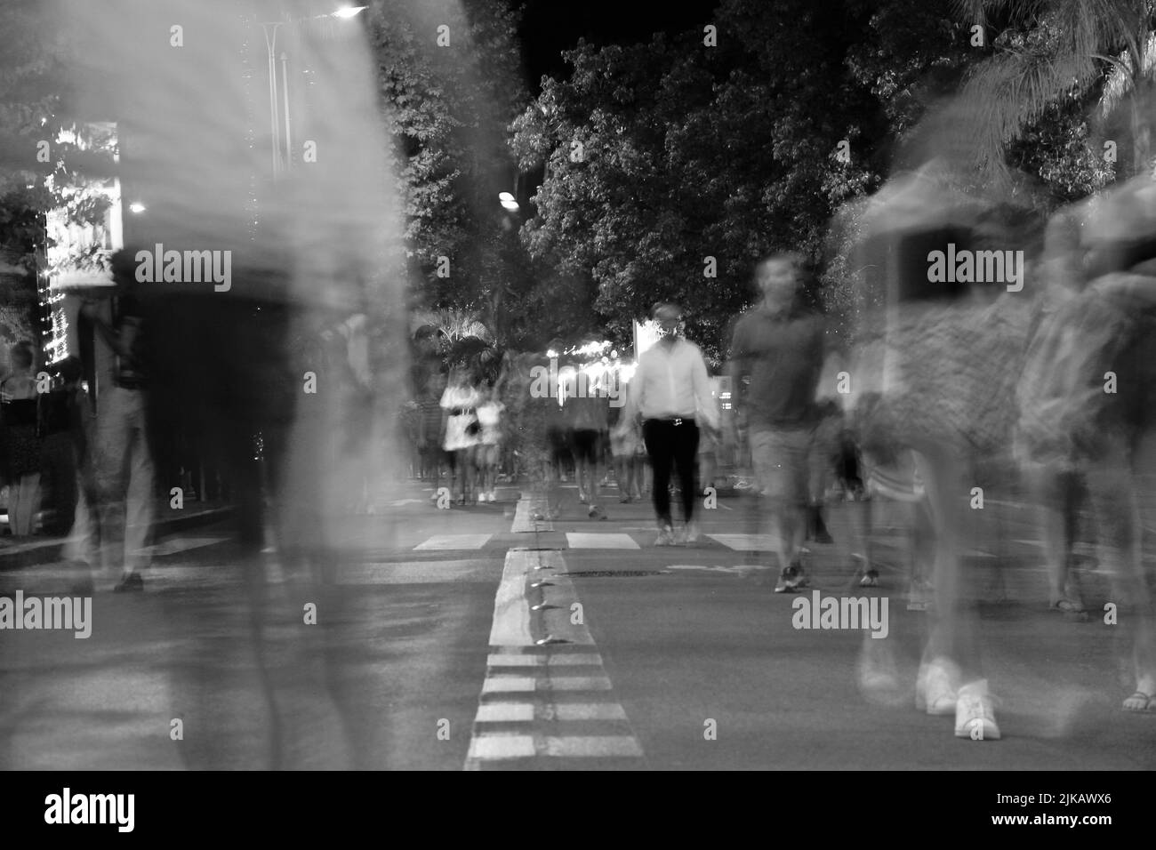 Long exposure of medium long shot of people walking on the road at night in Cannes. Stock Photo