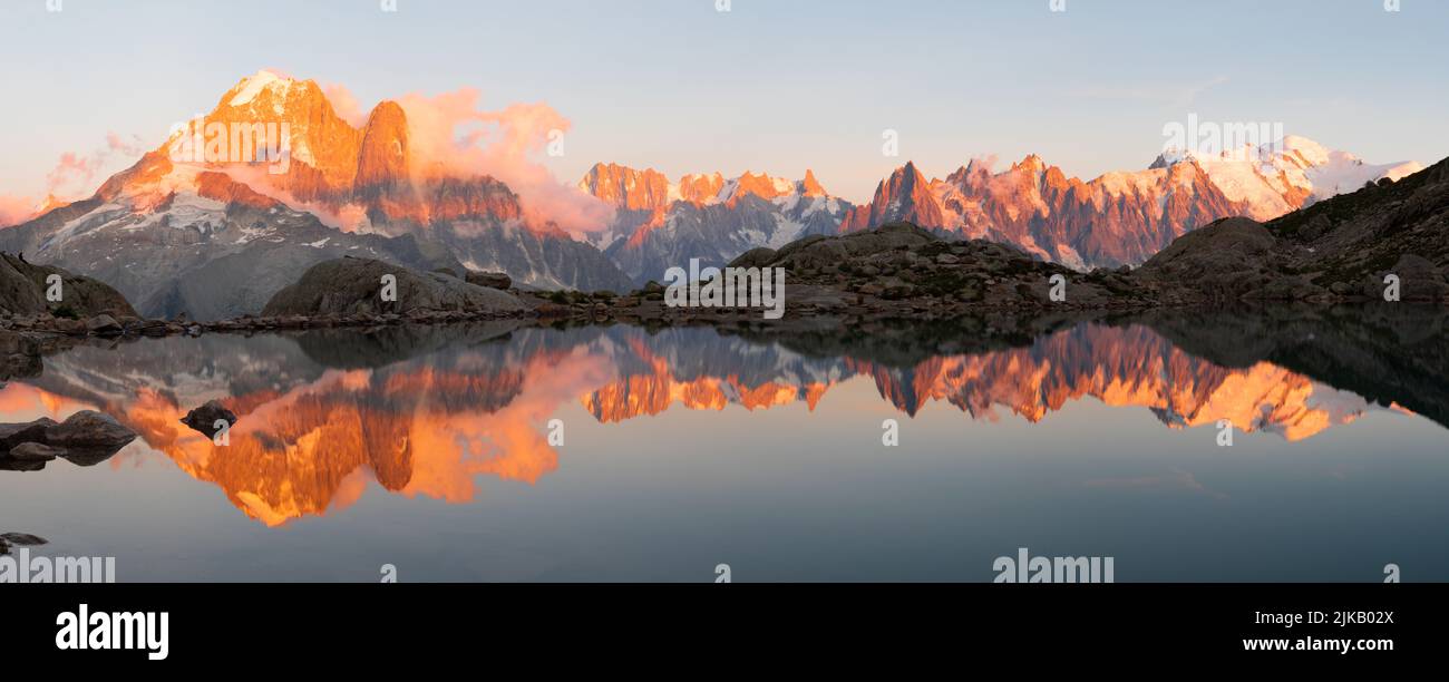 The panorama of Mont Blanc massif  Les Aiguilles towers, Grand Jorasses and Aiguille du Verte over the Lac Blanc lake in the sunset light. Stock Photo